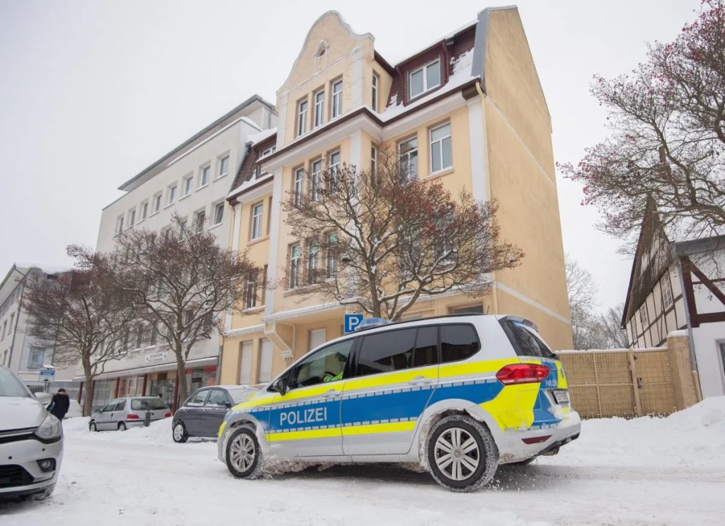 Ein Polizeifahrzeug steht vor einem Mehrfamilienhaus in der Innenstadt. Nach dem tödlichen Überfall auf eine 83-Jährige in Peine haben Ermittler am Tatort Spuren gesichert.