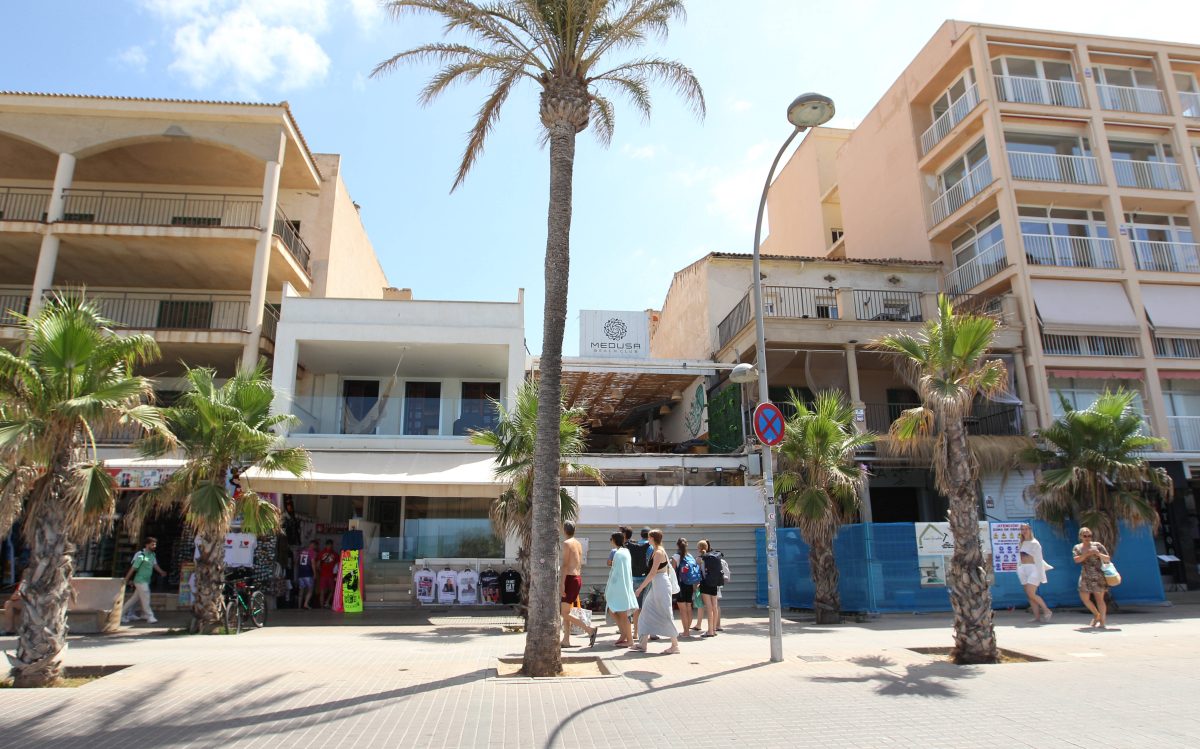 Menschen gehen an der Playa de Palma entlang. Im Hintergrund ist der Medusa Beach Club zu sehen.