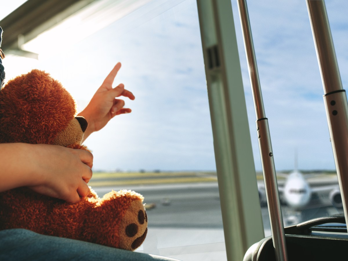 finger pointing towards the sky and showing the plane while waiting at airport terminal.