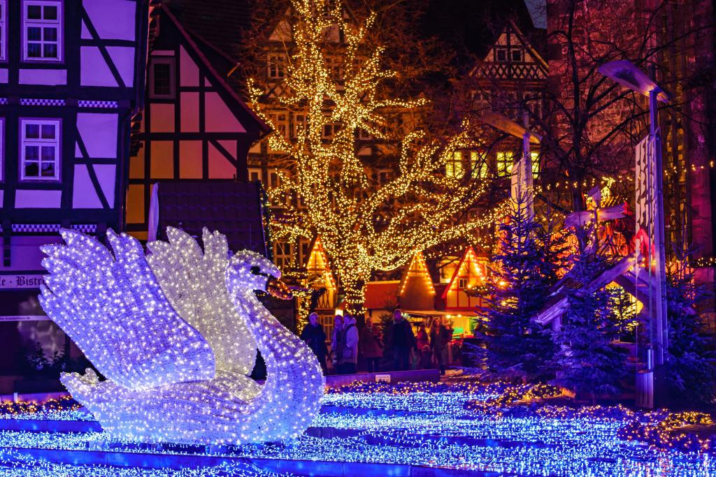 Eine Schwan-Lichterfigur vor beleuchtetem Weihnachtsmarkt