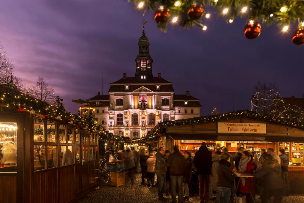 Beleuchtetes Rathaus in Lüneburg, davor steht eine Hütte mit Glühwein