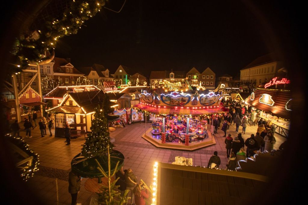 Ein Kinderkarussell steht auf einem beleuchteten Weihnachtsmarkt