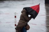 Eine Frau hat aufgrund starker Windböen Probleme ihren Regenschirm festzuhalten. (Symbolbild) für das Wetter in Niedersachsen.